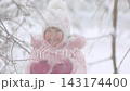 A child is having fun outdoors in winter forest. A little girl plays in a nature park against a snow covered trees background. Healthy lifestyle and winter holidays concept. 143174400