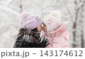 Mother and child are having fun outdoors in winter forest. A family plays in a nature park against a snow covered trees background. Healthy lifestyle and winter holidays concept. 143174612