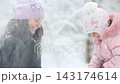 Mother and child are having fun outdoors in winter forest. A family plays in a nature park against a snow covered trees background. Healthy lifestyle and winter holidays concept. 143174614