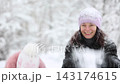 Mother and child are having fun outdoors in winter forest. A family plays in a nature park against a snow covered trees background. Healthy lifestyle and winter holidays concept. 143174615