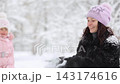Mother and child are having fun outdoors in winter forest. A family plays in a nature park against a snow covered trees background. Healthy lifestyle and winter holidays concept. 143174616