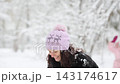 Mother and child are having fun outdoors in winter forest. A family plays in a nature park against a snow covered trees background. Healthy lifestyle and winter holidays concept. 143174617