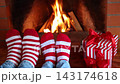 Feet dressed in wool socks with a Christmas ornament in front of the fireplace. The couple is having fun at home on Christmas Eve 143174618