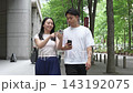 一對男女正在城裡約會散步，他們各自看著智慧型手機上的地圖應用程式。 143192075