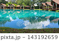 Video footage of luxury tropical villas surrounding an outdoor swimming pool, demonstrating landscape ecology, residential architecture, resort design, and water reflection physics 143192659