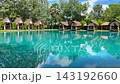 Video footage of luxury tropical villas surrounding an outdoor swimming pool, demonstrating landscape ecology, residential architecture, resort design, and water reflection physics 143192660