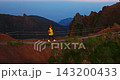 Aerial view of young woman in a yellow jacket and a backpack is hiking up a mountain, surrounded by incredibly beautiful scenery high up in the mountains. A concept of travel and an active lifestyle 143200433