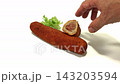 Close-up shot of hand picking up a piece of crispy deep-fried Spanish flamenquin pork roll with ham and cheese filling, isolated on a clean white background. Ideal for Mediterranean cuisine promotions 143203594