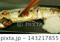 Enjoying grilled saury by flaking the flesh with chopsticks – a Japanese autumn meal served with grated daikon radish. 143217855
