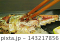 Enjoying grilled saury by flaking the flesh with chopsticks – a Japanese autumn meal served with grated daikon radish. 143217856