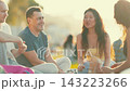 Friends gather at the beach to talk and enjoy snacks during sunset 143223266