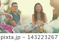 Diverse group of friends enjoying picnic at sunset 143223267
