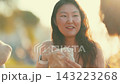 Friends enjoying food together at sunset in an outdoor location 143223268