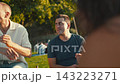 Group gathers in park for summer afternoon, sharing stories and enjoying relaxed atmosphere 143223271