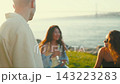 Friends gather at the waterfront to enjoy drinks and conversation during sunset 143223283