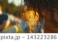 Woman enjoying the sunlight in a park during a summer afternoon with curly hair shining 143223286