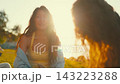 Friends enjoy a summer evening by the water while talking and laughing with the sun setting behind them 143223288