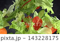 Fresh green salad with lettuce arugula and cherry tomatoes fly through the air in super slow motion against a dark background 143228175