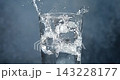 Ice cubes falling into a glass of water creating splash in super slow motion 143228177