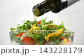 Olive oil pouring from bottle onto fresh vegetable salad slow motion 1000 fps white background 143228179