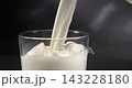Milk pouring into glass creating a splash in slow motion close up black background 143228180
