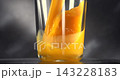 Fresh orange juice pouring into clear glass in slow motion against black background 143228183