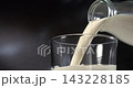 Milk pouring into glass creating a splash in slow motion close up black background 143228185