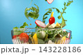 Fresh vegetable salad ingredients falling into glass bowl in slow motion 1000 fps on bright blue background 143228186