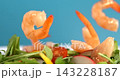 Shrimp falling onto fresh vegetable salad with avocado on blue background slow motion 1000 fps 143228187