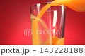 Fresh fruit juice pouring from bottle into clear glass in slow motion against red background 143228188