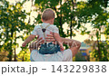 Carefree dad with kid son preschool age play, sun in park. Son sits on shoulders of father. Happy family, Fathers Day. Leisure for child. Parent dad, cute little baby boy fun. Family holiday, parent 143229838
