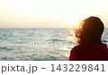 Young woman looking ocean, ocean vessel rocking on waves. Lady in red dress enjoys ocean sunset on deck ship. Yacht sails on sea, woman travels on ship. Sea voyage. Woman hair is blown by wind, water 143229841