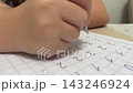 Horizontal close up view of child hand writing number three in math copybook with pen during back to school study process at desk in room. 143246924