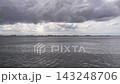 Cargo Ships Anchored at Sea Under Storm Clouds.Commercial cargo vessels and oil tankers anchored on calm sea waters under dramatic cloudy overcast sky. Cargo Ships Anchored at Sea Under Storm Clouds.Commercial cargo vessels and oil tankers anchored on calm sea waters under dramatic cloudy overcast sky. 143248706