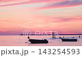 Stunning vibrant sunset sky over calm sea water with silhouette small fishing boats moored peacefully at twilight hour. Adriatic sea near the city of Vlore in Albania, Europe. 143254593