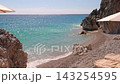 Stunning secluded tropical beach with crystal clear turquoise water, gentle waves, rocky cliffs, and relaxing loungers. Dhermi beach near the city of Vlore in Albania, Europe. 143254595