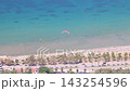 Aerial view of colorful paraglider flying over sunny tropical beach resort coastline with clear turquoise ocean water. Seaside landscape near the city of Vlore in Albania, Europe. 143254596