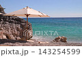 Stunning tropical beach landscape featuring a beach umbrella, rocky cliffs, clear turquoise sea, and sunny coastline. Dhermi beach near the city of Vlore in Albania, Europe. 143254599