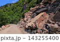 Mountain road crosses cliffs, wide view of an unpaved route between exposed rock and forest in Georgia, documenting rural transport access, remote infrastructure and travel conditions 143255400