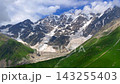 Shkhara Glacier descending in wide view above green alpine slopes near Ushguli, Svaneti, Georgia, travel scene for trekking routes, glacier tourism, mountain geography, and outdoor destination 143255403