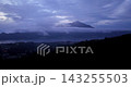 Cinematic aerial drone footage filmed at sunrise from Mount Batur summit with Mount Agung rising in the distance. Golden morning light reveals Bali's volcanic terrain and scenic mountain landscape 143255503