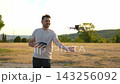 Asian woman operates a drone in a sunny park during the afternoon 143256092