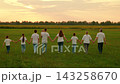 Large group happy people walk hand in hand green grass. Father mother, children strolling park lawn. Family love, parents dad mom, children son, daughter walking outdoors on summer evening at sunset. 143258670