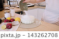 Cooking cheesecake. Dessert preparation. Baker woman hand adding measured salt sugar portion to bowl with dough ingredient in modern kitchen. 143262708