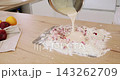 Berry pastry preparation. Baking cake. Female chef pouring liquid batter from bowl in flour crumbs cranberry pile on wooden table. 143262709