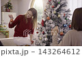 Happy woman preparing Christmas tree decorations with family 143264612