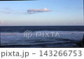 Ocean waves roll toward quiet shore beneath soft clouds in calm coastal light. Gentle surf creates peaceful seaside view, inviting relaxation beside open water and distant horizon. 143266753