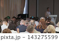 Conference audience between a lectern and projection screen 143275599
