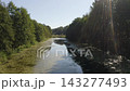 Forward drone glide above a pond between wooded banks 143277493
