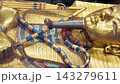 Tutankhamun's golden burial mask featuring blue inlays, a headdress, and arms crossed over the chest holding a crook and flail 143279611